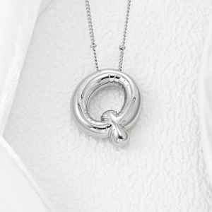 Macro shot of polished silver balloon letter Q pendant with realistic knot detail