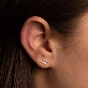 Close-up of gold S925 silver C-shape earring with sparkling zircons on female ear lobe