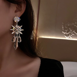 Detailed view of silver needle drop earrings with sparkling crystals and floral tassels