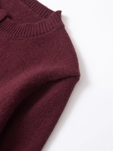 Detail of burgundy knit sweater showing ribbed crew neck and fine stitching texture