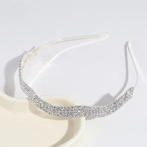 Close-up of sparkling silver headband with rhinestones on white ceramic stand
