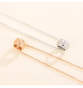 Macro detail of rose gold and silver cylinder pendants with diamond-pattern engraving