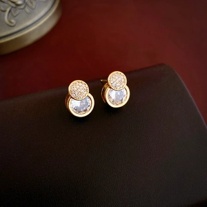 Elegant gold plated geometric earrings featuring round cubic zirconia on leather backdrop
