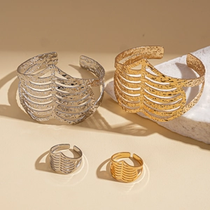 Detailed view of hammered hollow metal cuff bracelet and ring set in gold and silver