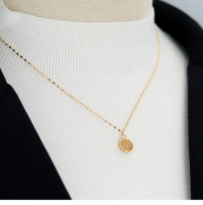 Close-up of a delicate 18K gold-plated titanium necklace with a round natural agate stone