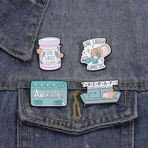 Set of 4 mental health enamel pins with supportive quotes on a blue denim jacket pocket