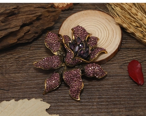 Macro view of vintage gold flower brooch with purple rhinestones on a rustic wood background