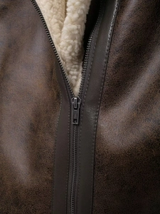 Detail shot of vintage brown leather jacket featuring soft sherpa lining and metal zipper