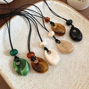 Close-up of teardrop acrylic bead pendants in diverse colors on wax rope necklaces