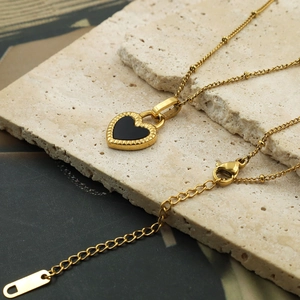 Macro shot of gold plated heart pendant with black enamel inlay on natural stone