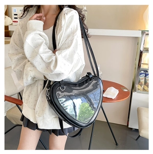 Detail of heart-shaped Ita bag in black PU leather with transparent PVC window on a model