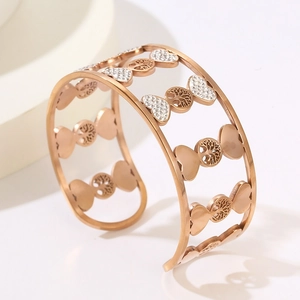 Macro detail of rose gold life tree and heart-shaped patterns on wide cuff bracelet