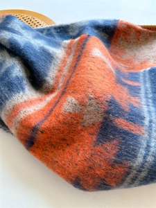 Detailed macro view showing the soft plush texture and blue orange plaid pattern of the scarf