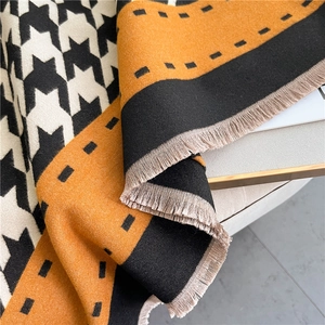 Detailed macro view of orange and black houndstooth scarf with elegant fringe edges