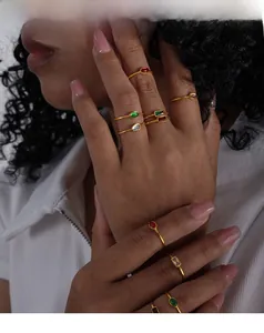 Close-up of slim gold titanium rings with colorful gemstone accents worn by a model