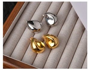 Macro detail of teardrop earrings in gold and silver finish on beige velvet