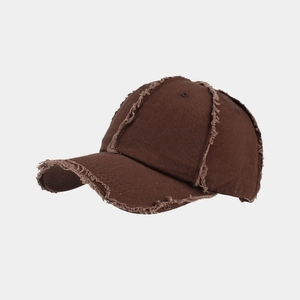 Close-up of coffee brown baseball cap featuring distressed frayed edges and cotton texture