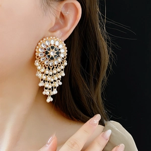 Close-up of vintage golden drop earrings with pearls and Kundan stones on a model