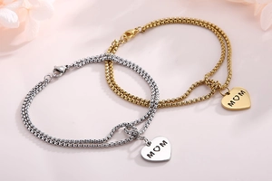 Detailed close-up of gold and silver heart-shaped MOM pendants on layered pearl chains