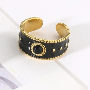 Detailed top view of wide black enamel ring with golden accents and center gemstone