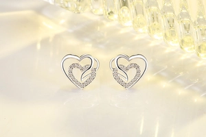 Macro view of double heart stud earrings with sparkling cubic zirconia in silver finish