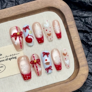 Christmas themed coffin nails set with 3D red bows and snowflake designs on wooden tray