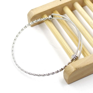 Detailed view of silver braided stainless steel wire bracelet on a bamboo stand