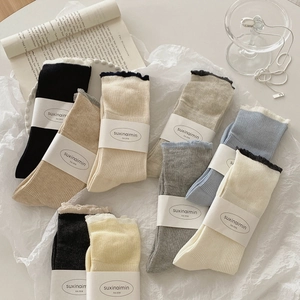 Japanese style ruffle socks in multiple colors like cream and blue on white paper background