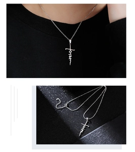 Close-up of silver stainless steel cross pendant necklace with artistic lettering
