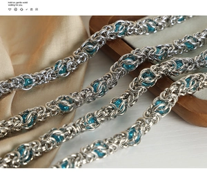 Macro shot of silver metal dragon bone chain links with blue beads on silk and wood