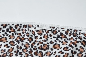 Détail d'un haut court léopard avec nœud en satin blanc et bordure en dentelle