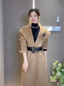Close-up of a black wide elastic belt with gold buckle styled on a camel wool coat