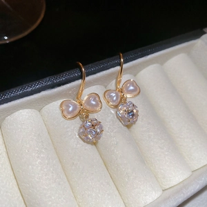 Detail of gold bow earrings featuring pink hearts and clear faceted zircon crystals