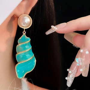 Detail of vintage conch earrings with turquoise drop and pearls on a female model