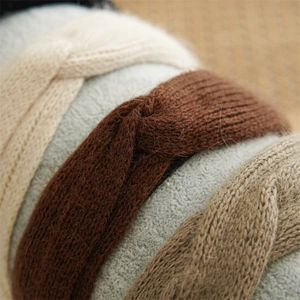 Detailed texture of knitted twist headbands in beige, brown, and khaki wool fabric