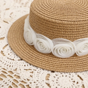 Detailopname van een strooien hoed met elegante witte gaasrozen en geweven textuur