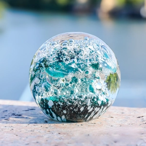 Close-up of glass wave sphere with blue swirls and bubbles on a stone surface