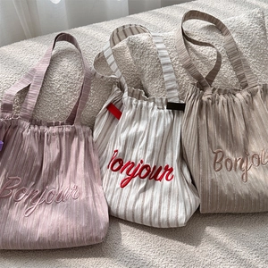 Detailed close-up of striped canvas tote bags with Bonjour embroidery and drawstring closure