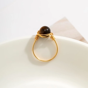 Detailed macro view of handmade gold wire-wrapped ring with a round tiger eye stone