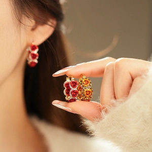 Detailed close-up of floral hoop earrings with red roses and sparkling crystal accents