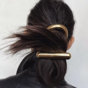 Detail of two vintage gold curved metal hair clips shown on a model's hair style