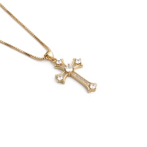 Macro shot of gold cross pendant with cubic zirconia stones on a box chain