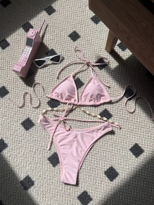 Pink bikini set with shell chain and sunglasses on polka dot rug with heart shadows