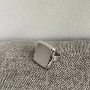 Macro shot of minimalist polished silver square ring with a smooth curved surface