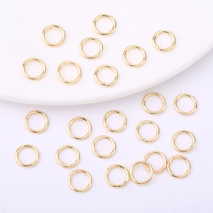 Polished 14K gold plated open jump rings scattered on white display tray for DIY jewelry