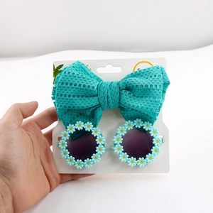 Close-up of mint green bow headband and white daisy sunglasses for baby girls