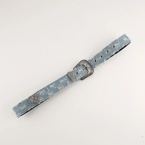 Close-up of blue denim belt with vintage carved buckle, sequins and distressed fringe detail