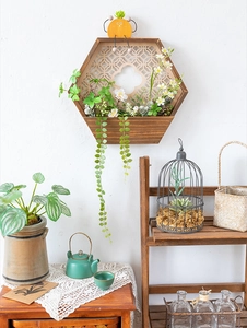 Detalle de macetero de pared hexagonal de madera con tallados y decoración de flores blancas