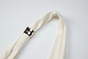 Détail de tissu en soie crème et boucle cylindrique en métal doré pour débardeur chic