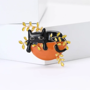 Cartoon enamel cat brooch on orange pumpkin with gold branches on white background